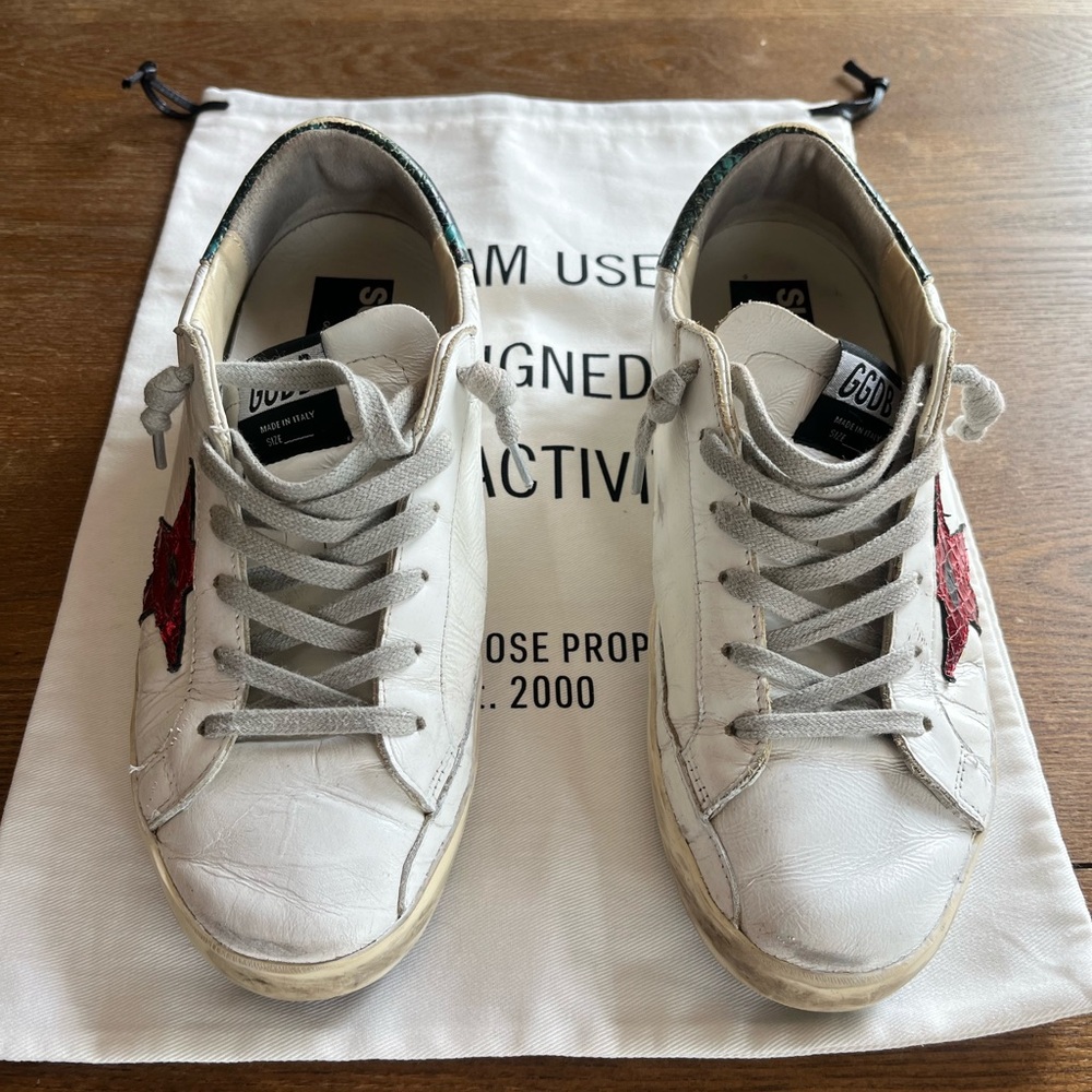 Golden Goose Superstar white leather with red metallic star and aqua heel tab.